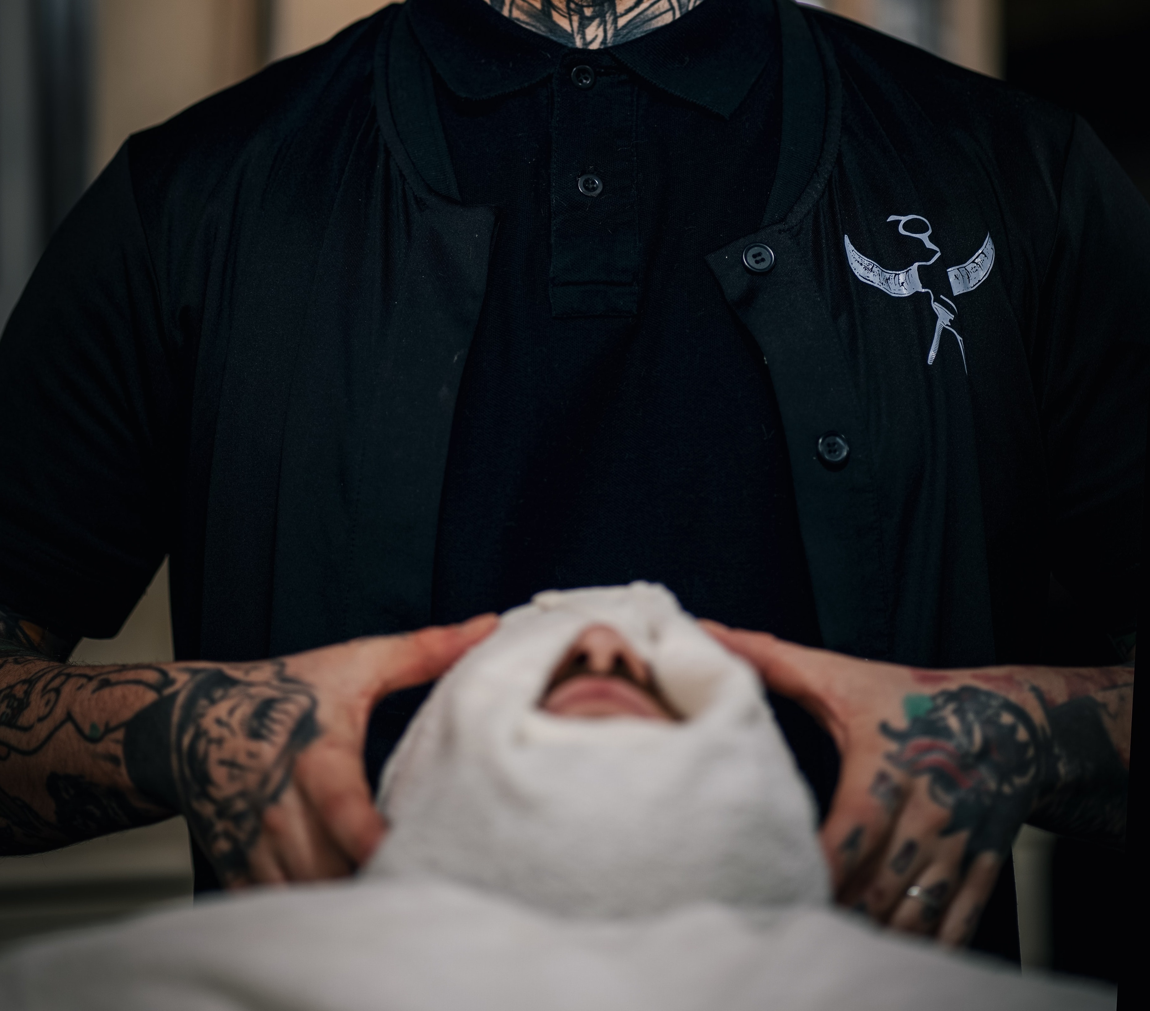 Barber putting hot towel on client's face